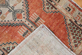 Distressed vintage Oushak rug's pale brick red geometric pile and hand knotted foundation.