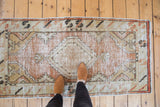 Vintage distressed Oushak rug, showing diamond medallion, floral spandrel, dusty rose and beige.