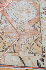 Distressed vintage Oushak runner with faded rose, sand, and black primitive patterns.