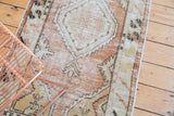 Distressed Oushak rug's faded dusty rose and beige tones, revealing geometric medallion and wear.