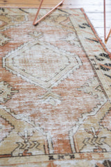 Distressed vintage Oushak runner showcasing faded dusty rose field and beige geometric patterns.