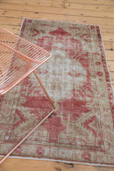 The soft, distressed texture of a vintage Oushak rug in dusty raspberry red and beige.