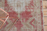 Worn, hand-knotted texture of a vintage rug in dusty raspberry red and beige.