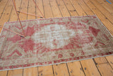Vintage distressed Oushak rug highlighting its decorative wear in raspberry red and beige.