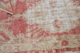 Soft, distressed texture of a vintage Turkish rug with faded raspberry and antique ivory tones.