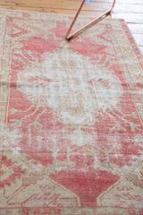 Soft focus on the faded raspberry red medallion and worn texture of a distressed vintage rug.