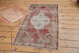 Distressed vintage Oushak rug in faded red and ivory, styled with a modern copper chair.