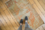 Upper corner of distressed vintage Oushak rug, showing tangerine orange and beige with mostly even wear.