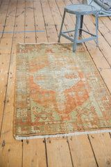 Distressed tangerine orange field, pale green geometric border, and fringe.