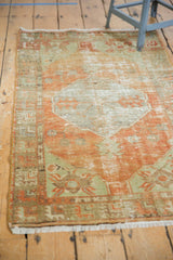 Distressed Oushak rug corner with worn pile, tangerine orange, and soft green border.