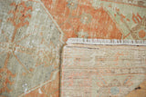 Distressed Oushak rug corner reveals tangerine pile, secure fringe, and woven reverse.