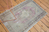 Decorative distressed Turkish Oushak rug with faded diamond medallion and soft mauve floral motifs.