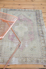 Distressed Oushak rug close-up with faded mauve and ivory floral medallion elements.