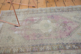 Distressed vintage Oushak rug pile, showing wear, diamond medallion, and faded mauve, ivory tones.