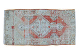 Vintage distressed Oushak rug runner with an artfully worn geometric medallion in faded red, seafoam green, and ivory, 2'6