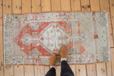 Distressed vintage Oushak runner, faded red stepped medallion and ivory field.