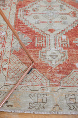 Detail of vintage distressed Oushak runner, showcasing faded red and ivory geometric patterns.