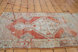 Distressed vintage Oushak runner with a stepped medallion in faded red and ivory.