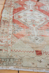 Lower border of distressed Oushak runner, with seafoam green and faded red geometric patterns.
