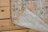 Corner of vintage distressed Oushak rug with hand-knotted foundation and secured side.
