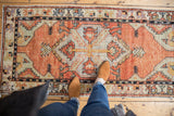 Distressed Oushak runner with a low pile, brick red, silver gray medallion, and serrated leaves.