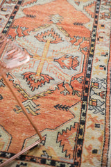 Detail of distressed Oushak rug: tangerine, silver, charcoal geometric pattern and worn pile.