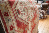 Distressed pile of vintage Turkish Oushak runner, showing cherry red abrash and geometric motifs.