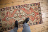 Distressed vintage Oushak runner, faded cherry red, charcoal, ivory, and abrashed floral border.
