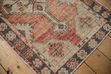 Distressed Oushak rug runner corner, showing primitive floral border with faded cherry red and charcoal tones.