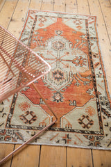 Distressed Oushak rug's textured pile and geometric pattern in cherry red and seafoam green.