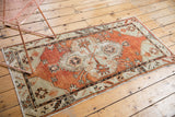 Distressed Oushak rug runner corner with softened cherry red and light beige motifs.