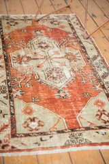 Textured pale cherry brick red field and seafoam green spandrel of vintage distressed Oushak runner.