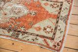 Distressed Oushak rug corner with geometric cherry brick red patterns and original selvage.