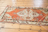 Textured corner of a distressed vintage Oushak runner with brick red, beige, charcoal geometric motifs, mostly even wear.