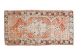 Vintage distressed Oushak runner, faded red diamond medallion, ivory field, and primitive charcoal borders.