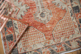 Distressed vintage Oushak rug texture, highlighting faded red, charcoal, and ivory geometric patterns.
