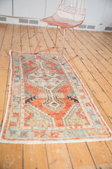 Distressed Oushak runner with faded cherry red, seafoam green geometric patterns.