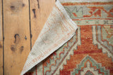 Hand-knotted Oushak rug reverse and worn pile with faded red and seafoam green patterns.
