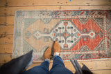Distressed vintage Oushak runner with faded diamond medallion in cherry red and seafoam.