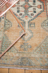 Distressed texture and abrash on the Oushak rug's primitive border with green and blue motifs.