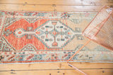 Distressed Oushak runner's abrashed end, showing muted peach, seafoam geometric motifs.