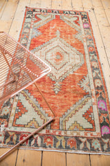 Distressed vintage Oushak runner with faded brick red field, visible wear, and playful floral border.
