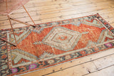 Distressed texture of vintage Turkish Oushak runner, faded brick red, pale floral border.