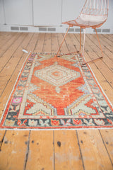 Faded brick red field and playful floral border of a distressed vintage Oushak runner.