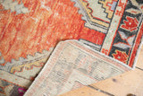 Distressed Oushak runner's faded brick red pile, visible foundation, and intact selvage.
