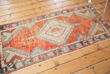 Distressed Oushak runner corner showing faded brick red pile, seafoam green spandrel, and abrashed border.
