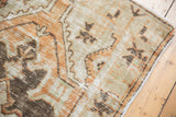 Distressed vintage Oushak rug corner, showing beige, terracotta, brown hues and intact selvage.