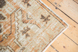 Vintage Oushak rug corner, showing distressed pile, intact selvage, and terracotta hues.