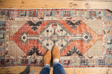 Distressed Oushak runner detail: abrashed cherry red field, ivory lattice spandrel, geometric border.