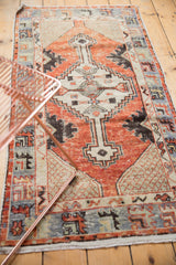 Distressed Oushak rug runner showing cherry red abrash, primitive border, and fringed end.